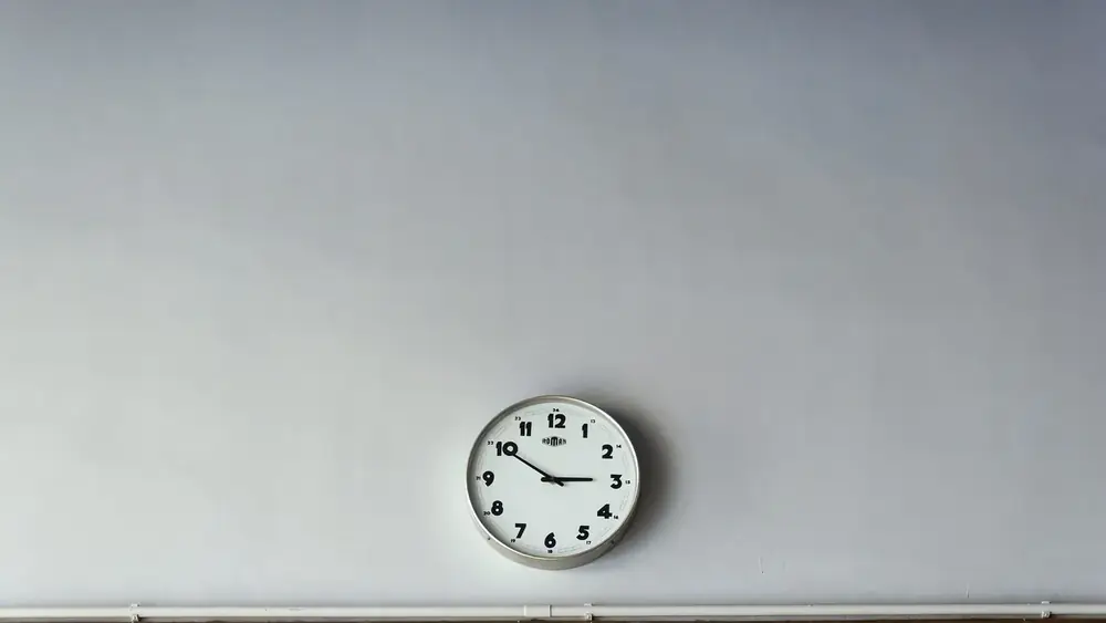 A round wall clock on a plain grey wall